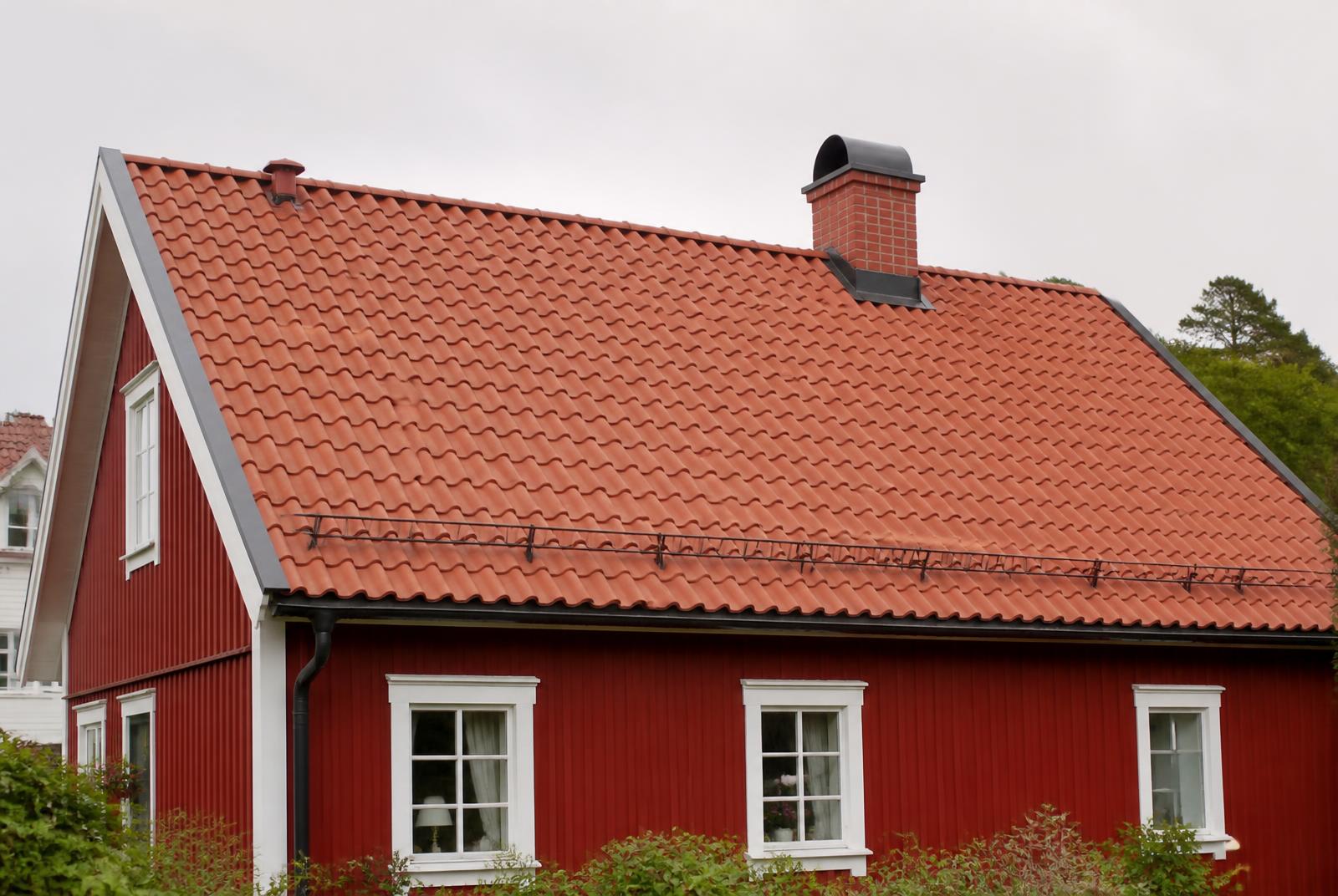 Villa med rött tegeltak, murad skorsten, snörasskydd och plåtdetaljer